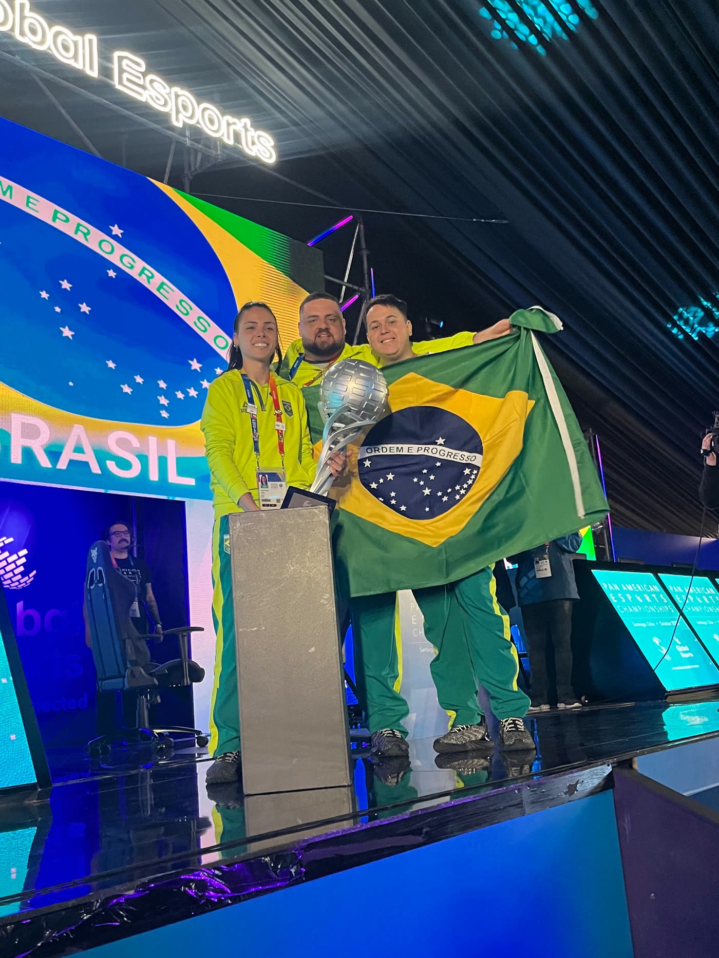 Vitor Abdalla no pódio do Pan-Americano de eSports em Santiago, com o troféu e a bandeira do Brasil